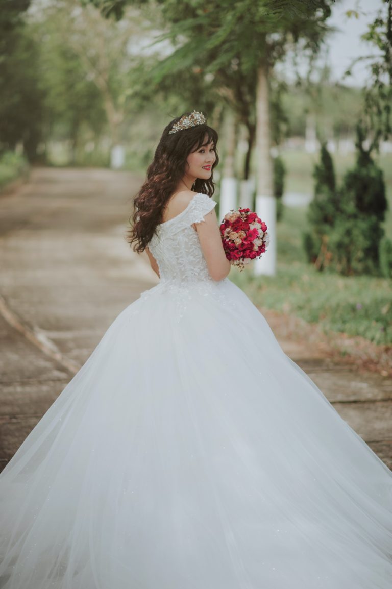 Josie posing on her wedding day holding red flowers.